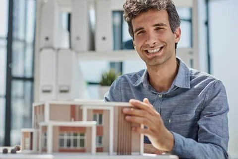 Young caucasian engineer man making building model with the use of drawings and Fotos de archivo