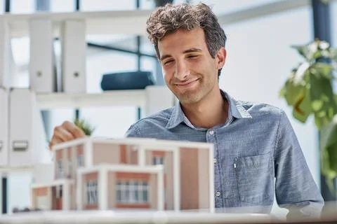 Young caucasian engineer man making building model with the use of drawings and Fotos de archivo