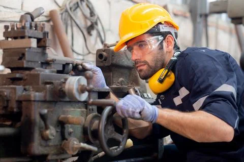 Young caucasian engineer man operating lathe machine for preparing producti.. Foto stock