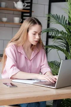 Young caucasian female using computer, looking at device screen, distance work Stock Photos