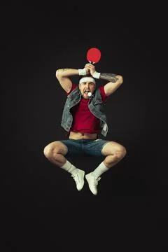 Young Caucasian funny man playing ping pong isolated on black background. Stock Photos