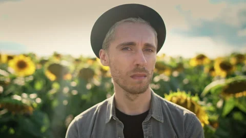 Young caucasian guy in black hat in a sunflower field on a sunny day Video stock 162858743