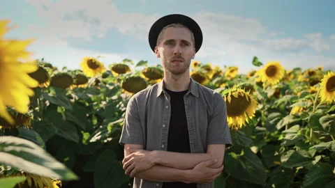 Young caucasian guy in black hat in a sunflower field on a sunny day Stock Footage 162961560