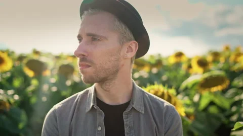 Young caucasian guy in black hat in a sunflower field on a sunny day Stock Footage 162961584