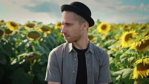 Young caucasian guy in black hat in a sunflower field on a sunny day Stock-Footage 162962205
