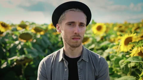 Young caucasian guy in black hat in a sunflower field on a sunny day Video stock 162962210