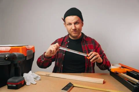 A young Caucasian guy a carpenter with a beard works in a carpentry workshop. Stock Photos