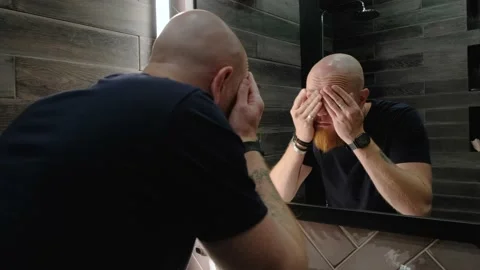 A young Caucasian guy examines himself in the mirror, smoothes his red beard. Stock Footage 138997979