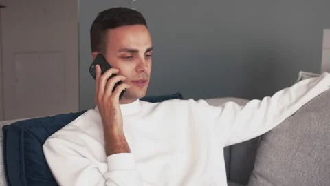 Young caucasian guy using phone relax on sofa at home Stock Footage 138903346
