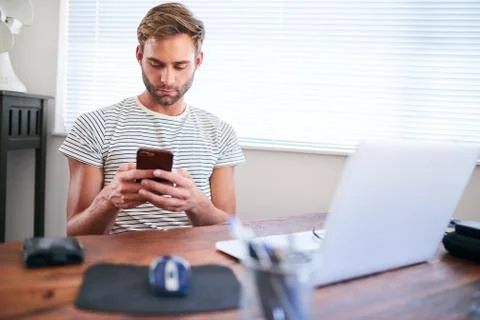 Young caucasian guy using phone while sitting at his desk Fotos Stock