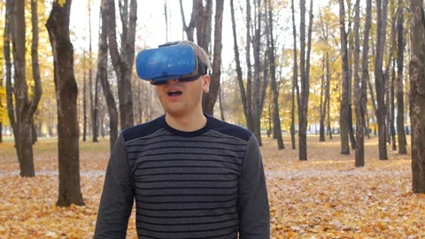 A young caucasian guy in virtual reality glasses examines the space around Stock Footage 129960853