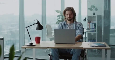 Young caucasian handsome disabled man in wheelchair sitting by desk using Stock Footage 149181053