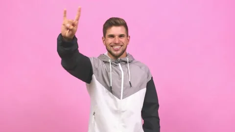 Young caucasian handsome man doing a rock gesture, enjoying life and laughing Stock Footage 138662317