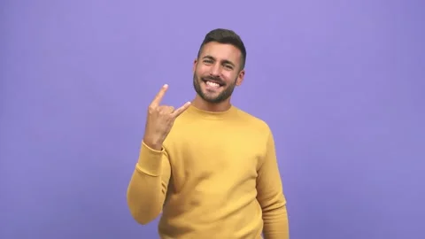 Young caucasian handsome man doing a rock gesture, enjoying life and laughing Stock Footage 138666433