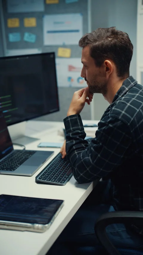 Young Caucasian male programmer writes code using multiple screens in office. Stock Footage 344036744