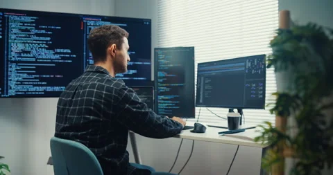 Young Caucasian male programmer writes code using computer in office. Vidéo 344037451