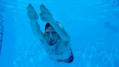 Young Caucasian man diving in the pool (240 fps slowmotion) 動画素材 115059549