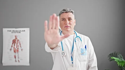 Young caucasian man doctor doing stop sign with hand at the clinic Stock Footage 246145341