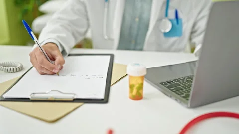 Young caucasian man doctor using laptop writing medical report at clinicc Video stock 247380628