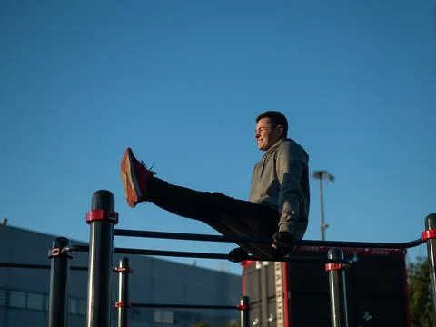 Young caucasian man doing parallel bars exercise outdoors. Stock Photos