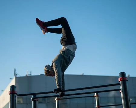 Young caucasian man doing parallel bars exercise outdoors. Stock Photos