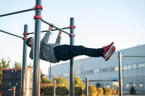 Young caucasian man doing parallel bars exercise outdoors. Stock Photos