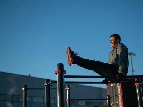 Young caucasian man doing parallel bars exercise outdoors. Stock Photos