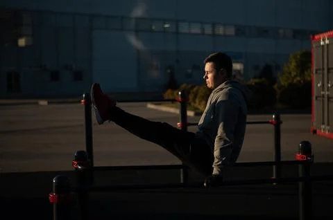Young caucasian man doing parallel bars exercise outdoors. Stock Photos