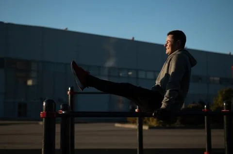 Young caucasian man doing parallel bars exercise outdoors. Stock Photos