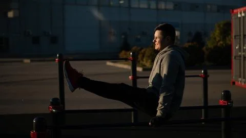 Young caucasian man doing parallel bars exercise outdoors. Stock Photos