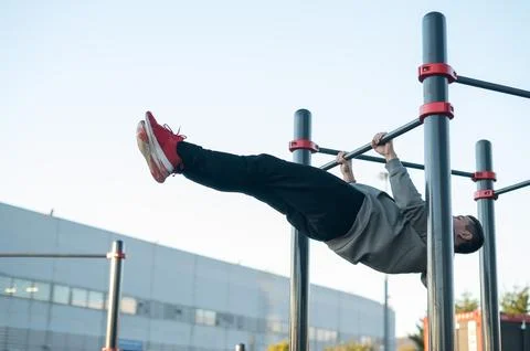 Young caucasian man doing parallel bars exercise outdoors. Stock Photos