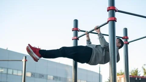 Young caucasian man doing parallel bars exercise outdoors. Stock Photos