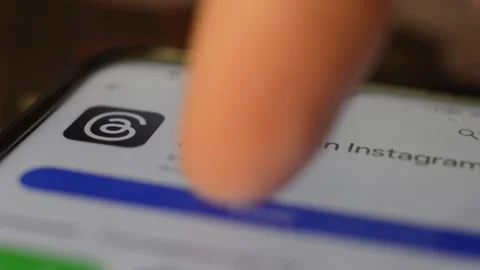 Young caucasian man download Threads by meta social network app on the phone. Stock Footage 258930683