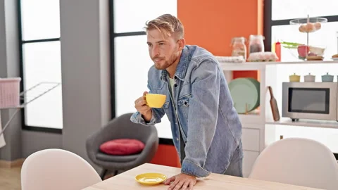 Young caucasian man drinking cup of coffee smiling at dinning room Stock Footage 247380549