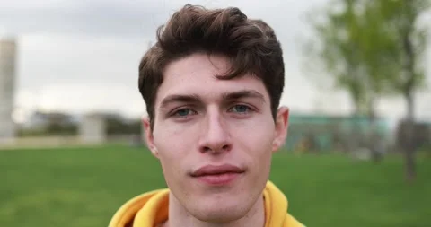 Young caucasian man looking on camera at city park Stock Footage 192384129