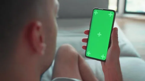 Young caucasian man lying on couch with modern smartphone in his hand while Stock Footage 241745188