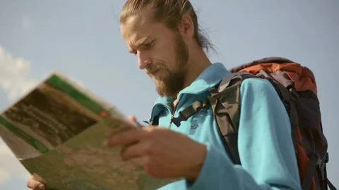 Young caucasian man with a map in his hands on a mountain trip. Stock Footage 116492844