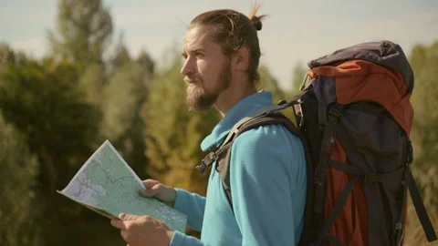 Young caucasian man with a map in his hands on a mountain trip. Stock Footage 116498512