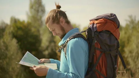 Young caucasian man with a map in his hands on a mountain trip. Stock Footage 116498539