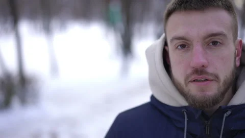 Young Caucasian man standing on the right in snowy winter park drinking coffee Video stock 219905955