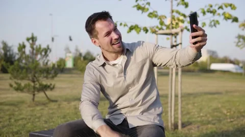 A young Caucasian man talks on a video call on a smartphone, waves his hand and Stock-Footage 147947405