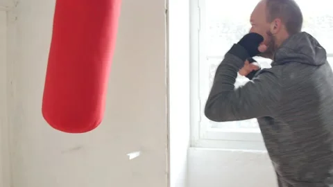 Young caucasian man throwing rapid punches at heavy bag in MMA home gym. A young Stock Footage 146455472