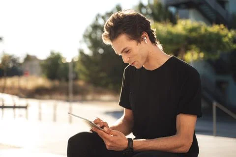 Young Caucasian man using digital tablet while sitting at university campus on Stock Photos