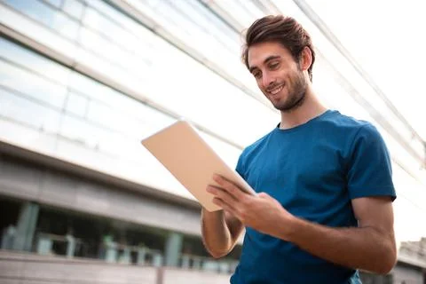Young caucasian man using digital tablet in business center of city. Copy space. Stock Photos