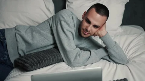 Young caucasian Man Using Laptop computer laughing on bed. Happy smiling man Stock Footage 144136961