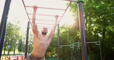 Young caucasian man using the monkey bars at at sports ground. Muscular man Stock Footage 157889757