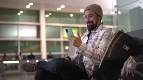 Young caucasian man using phone, doing a video-call at airport terminal. Stock Footage 235052503