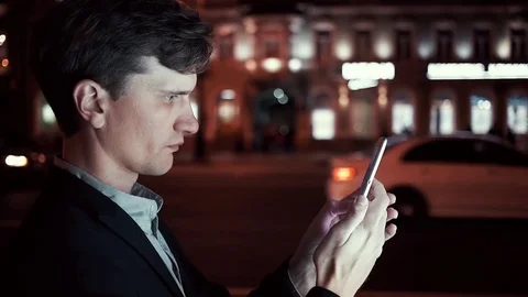 Young caucasian man using smartphone on a busy urban street in evening Stock Footage 80009668