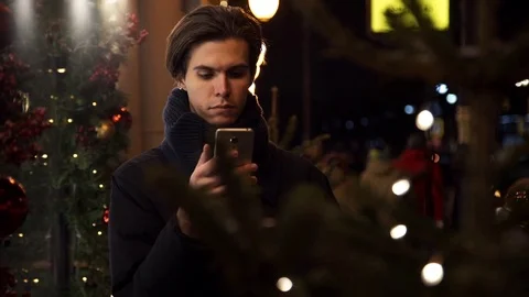 Young caucasian man using smartphone on a busy city street in evening Stock Footage 83630893