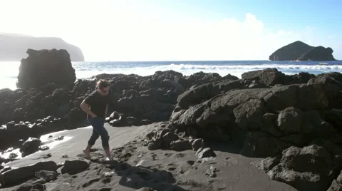 Young caucasian man walking away from the ocean Stock Footage 59337960